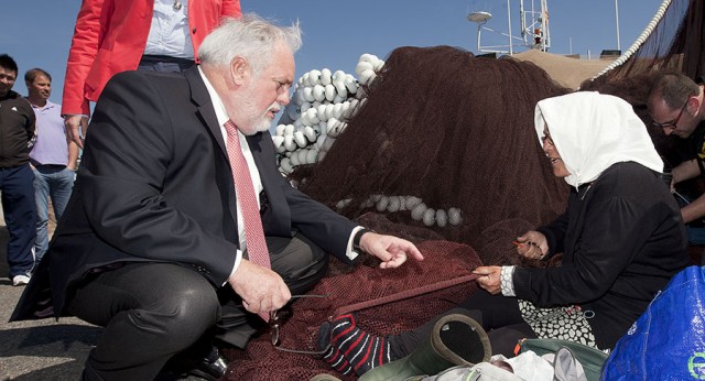 Miguel Arias Cañete conversa con una mujer que repara redes en el puerto de Cambados (Pontevedra)